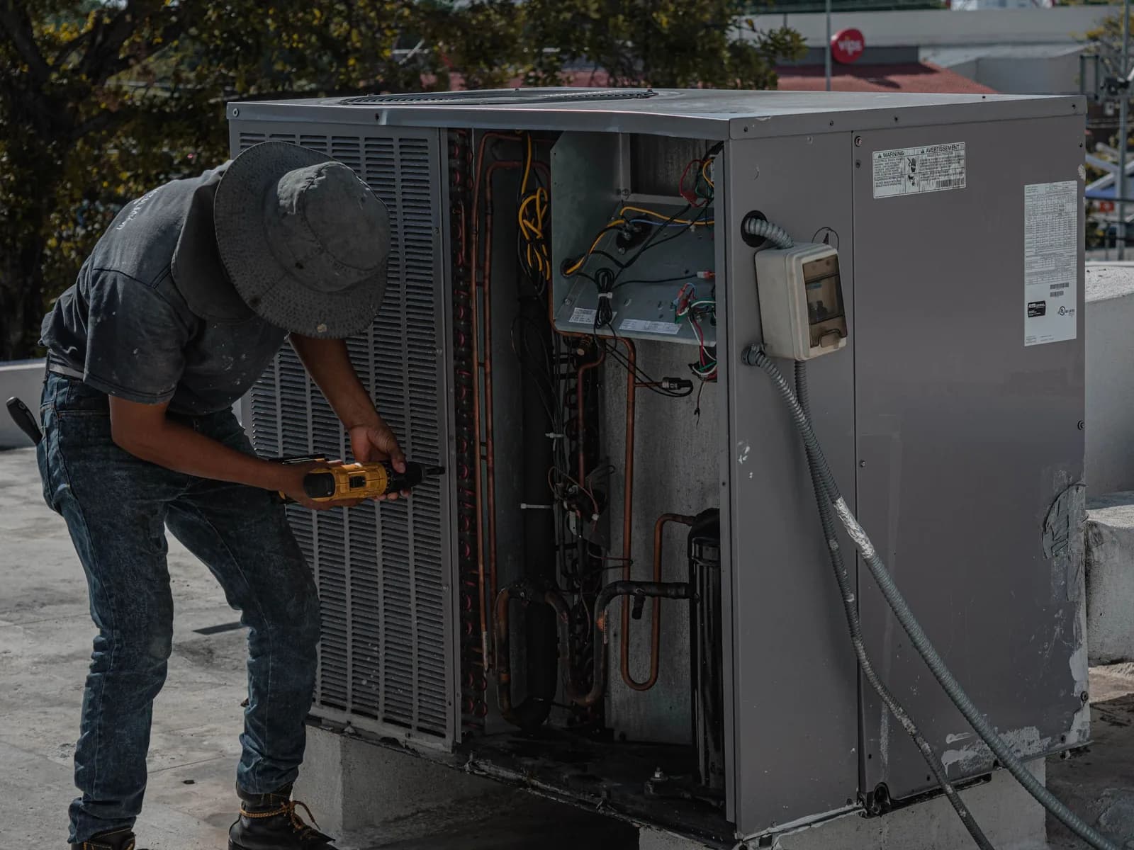 Technician working on a commercial rooftop HVAC unit with its service panel open