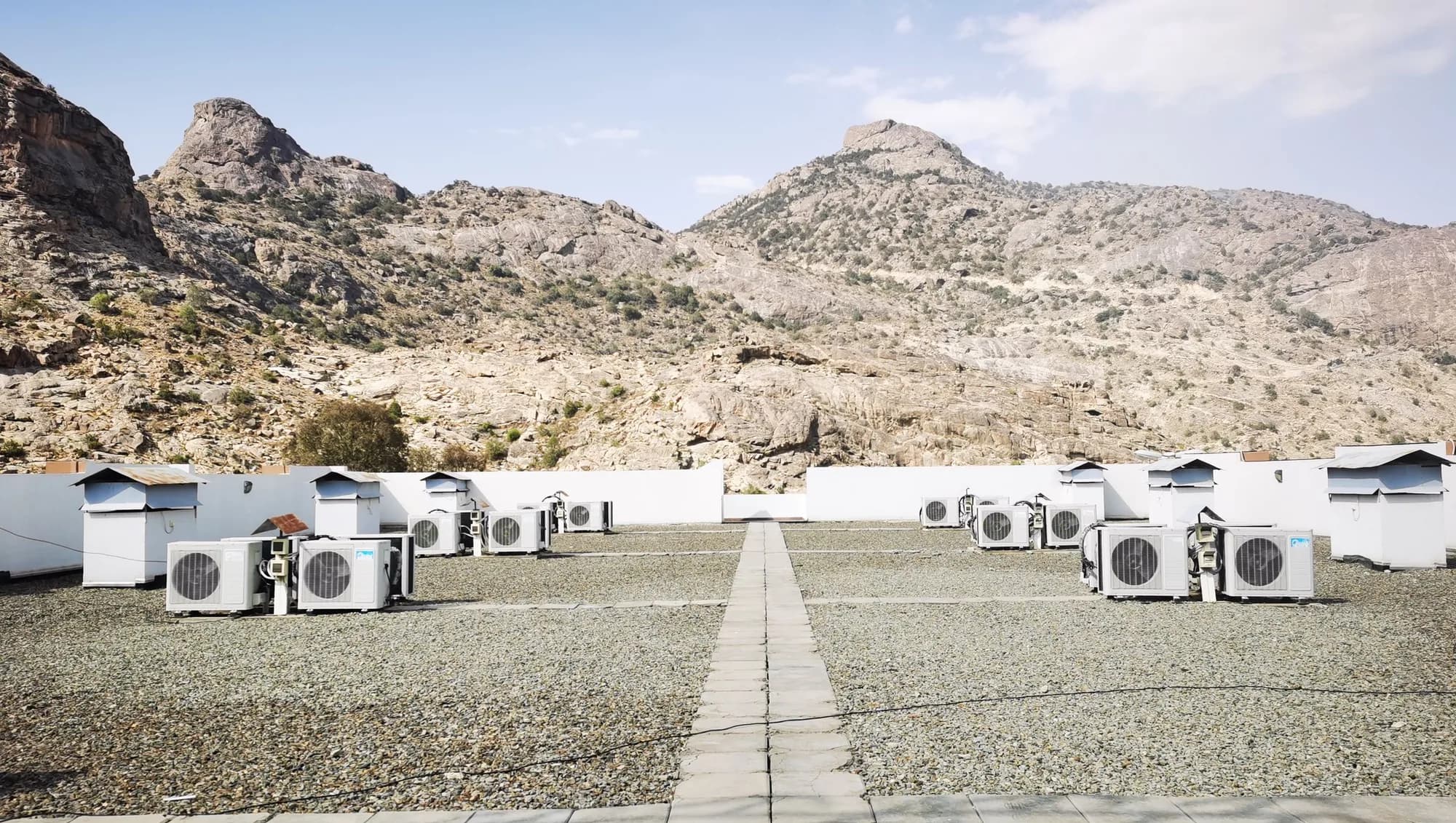 Air conditioning units on a rooftop in front of dry rocky desert mountains